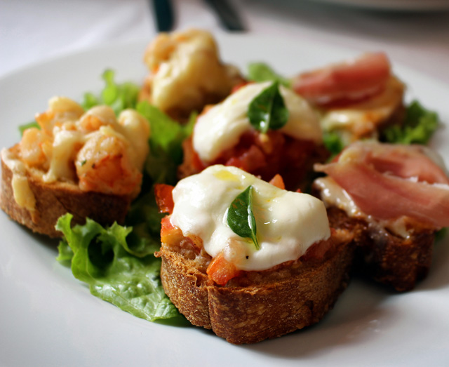 Trio de bruschettas: parma e parmesão, mussarela e tomate, camarão e queijo scamorza (R$ 20) 