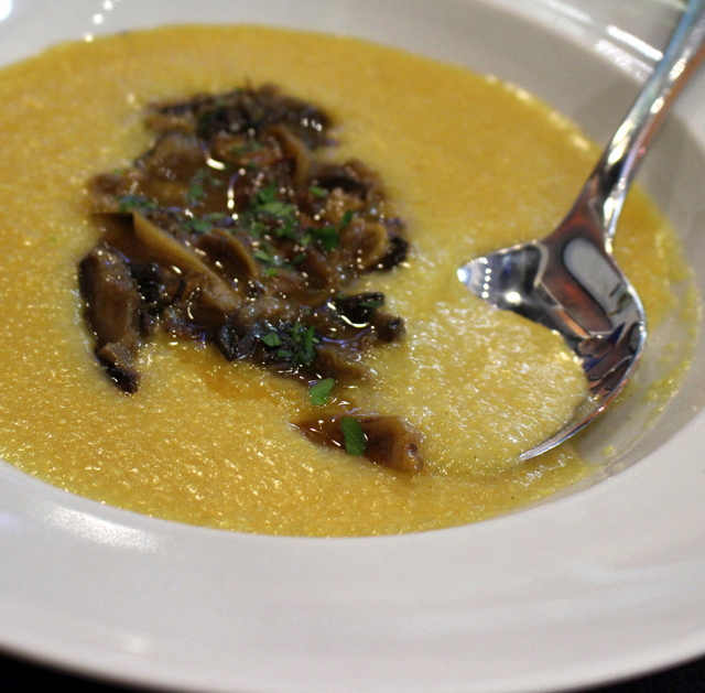 Polenta amarela, granulosa e saborosa, servida cremosa com misto de cogumelos 