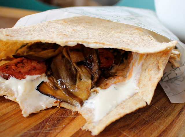 Piadina de massa integral recheada com linguiça, coalhada seca, tomate, berinjela em finas fatias e coentro