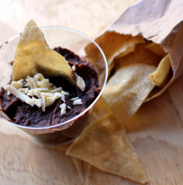 A deliciosa porção de Frijole refritos (feijão preto ao estilo mexicano com queijo e totopos, tortillas triangulares de milho, R$ 6) 