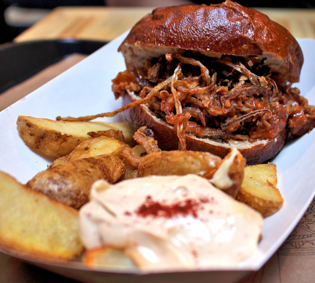 Suculentíssimo Schweinebrötchen (R$ 24): sanduíche de costela suína, curry e cebolas crocantes, no pão de pretzel, 