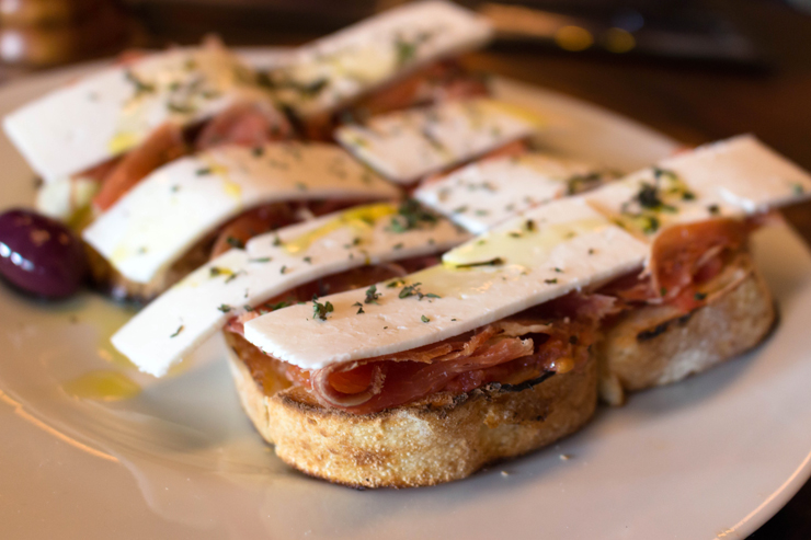 Porções para compartilhar no novo Adeguinha Santiago: Tostada na lenha de queijo de cabra e jamón serrano (R$ 38)