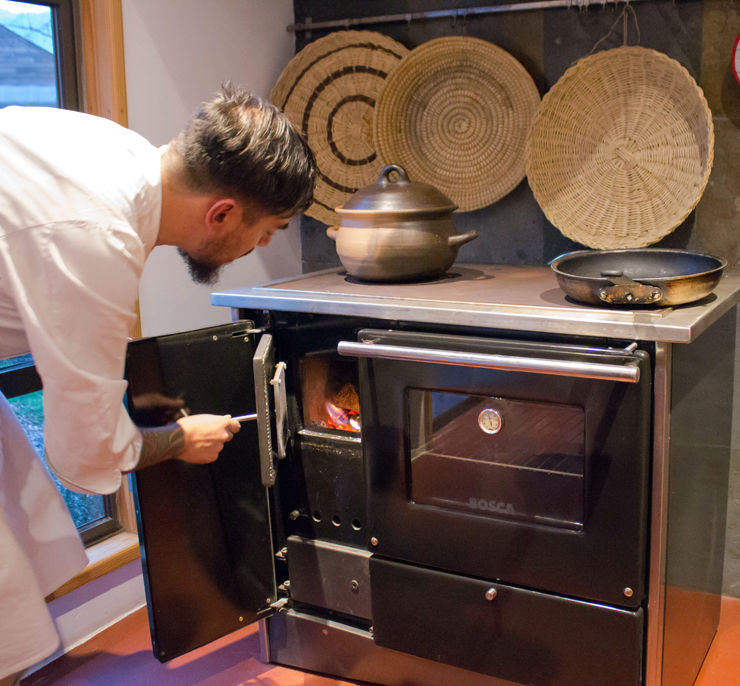 O chef Damian Fernandez acendendo o fogão a lenha para sua aula de culinária - todos os hóspedes podem fazer